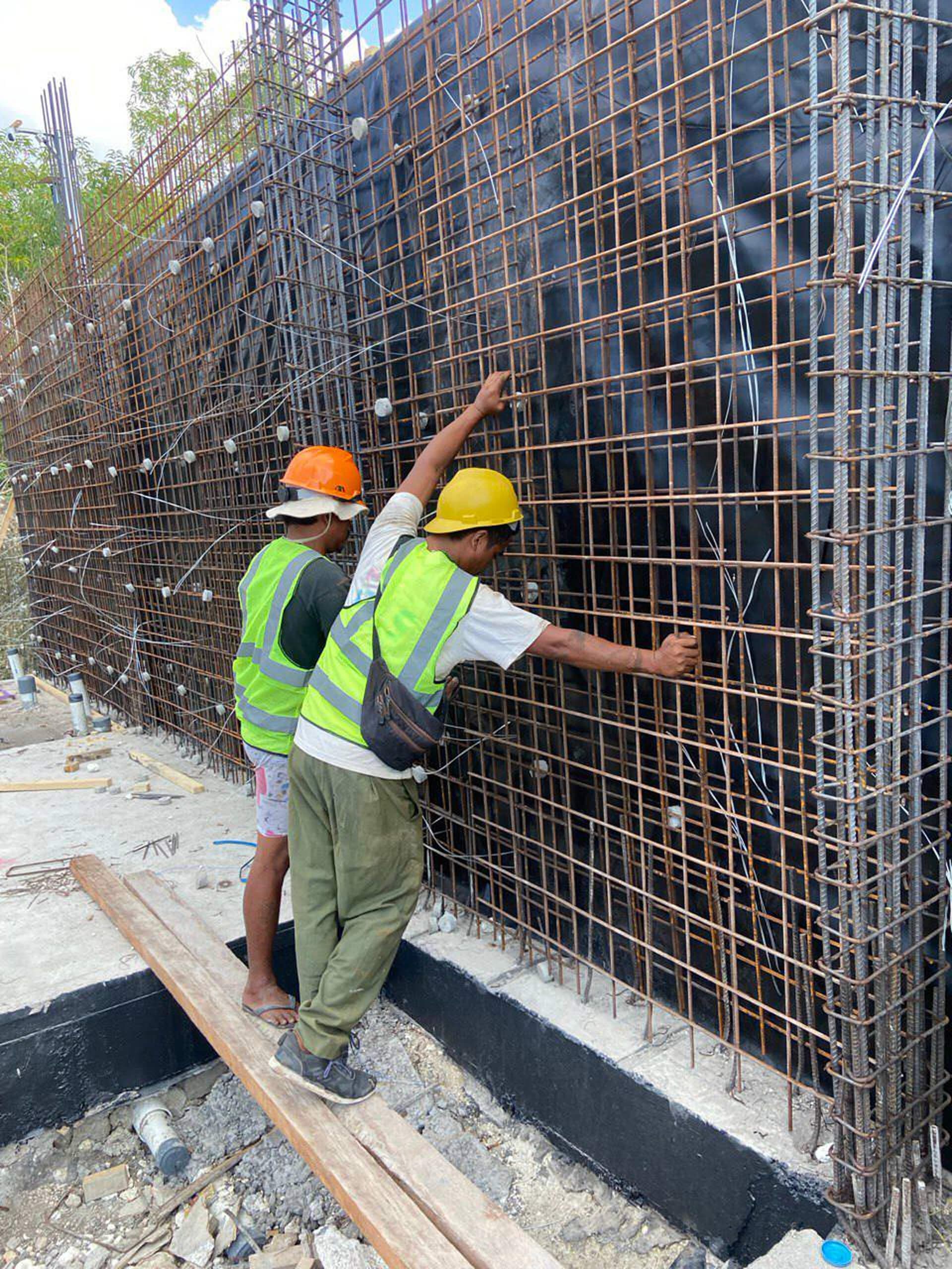 Construction progress — rebar cage of a retaining wall with workers — Frigate Bali