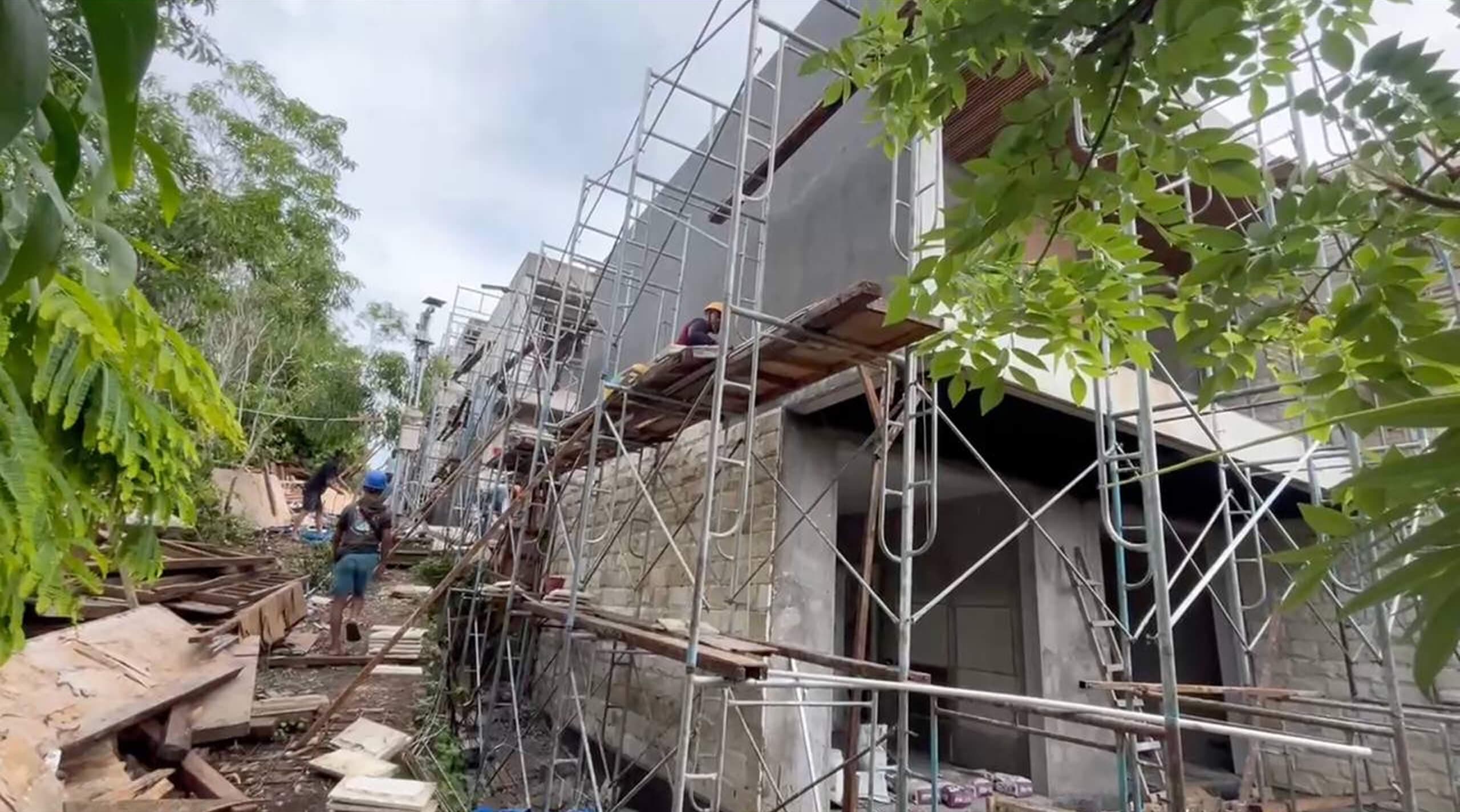 Construction progress — villa facade finishing on scaffolding with workers — Frigate Bali