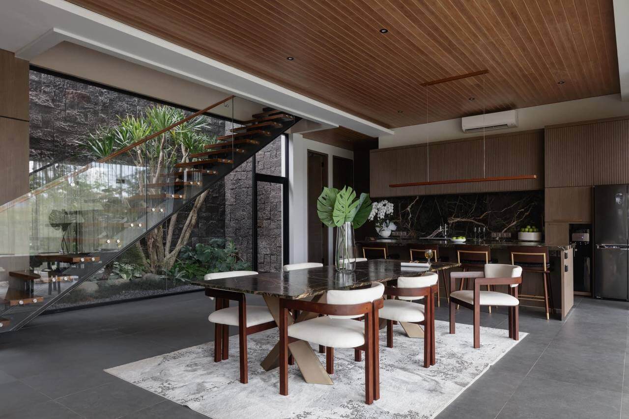 Villa dining area with marble table and open kitchen overlooking indoor garden — Frigate Bali